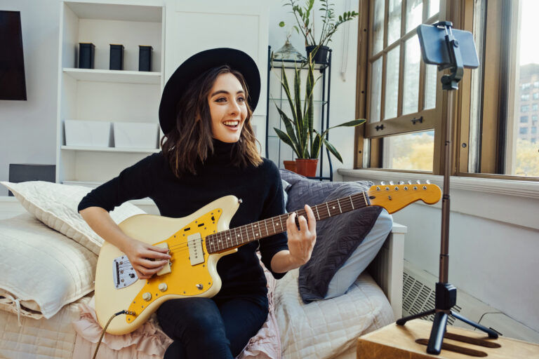 Young adult woman teaching guitar lesson online